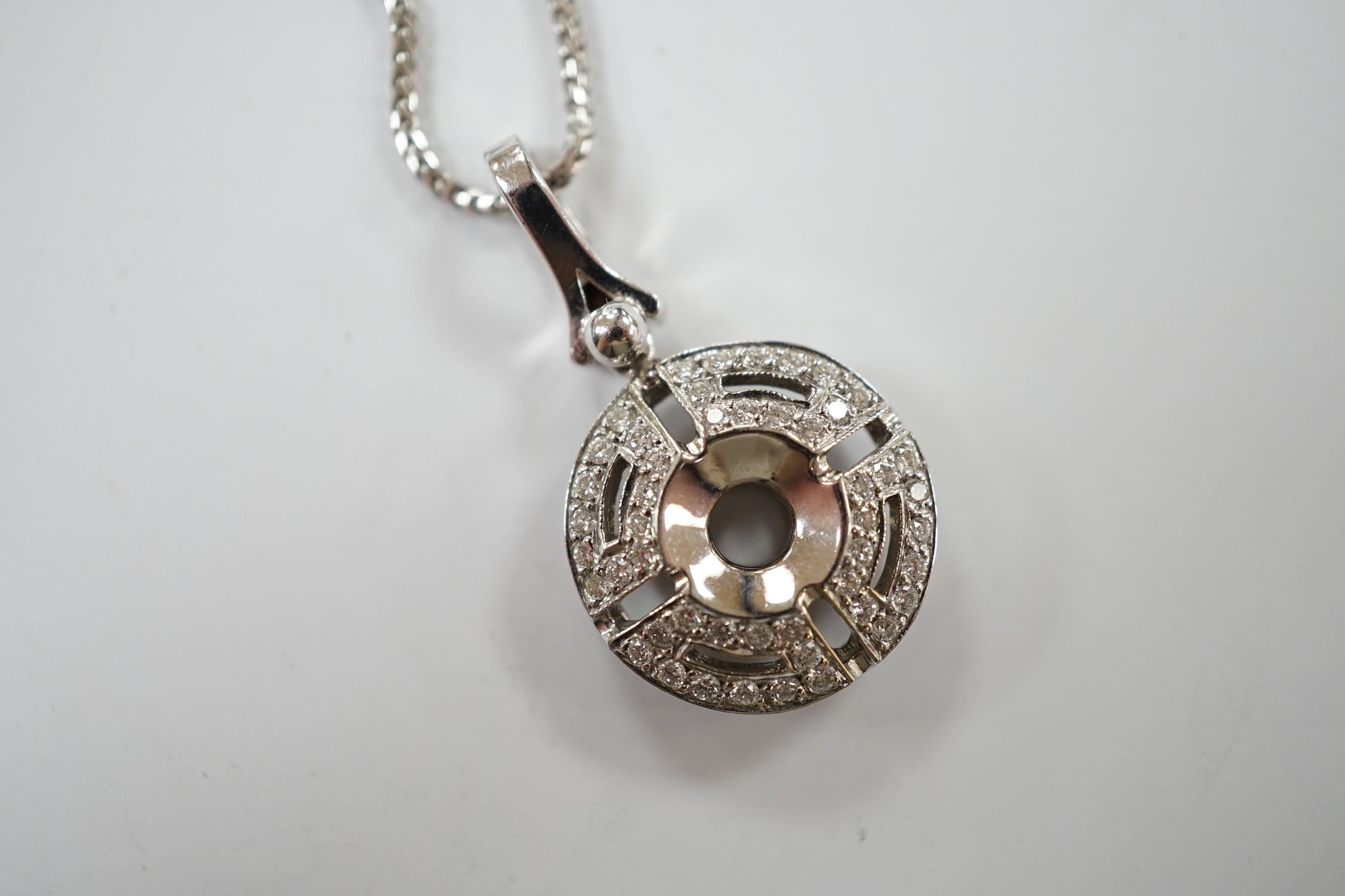 A modern pierced 18k white metal and diamond chip cluster set circular pendant, overall 29mm, gross weight 6 grams, on a 9k white metal chain, 45cm, gross weight 4 grams. Condition - good